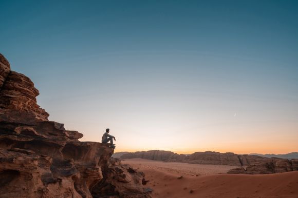 Adventure - a man sitting on a rock in the desert