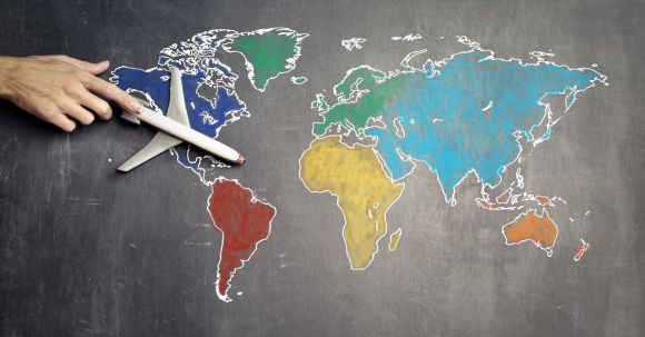 Solo Travel Guide - Top view of crop anonymous person holding toy airplane on colorful world map drawn on chalkboard