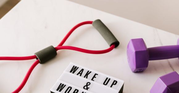 No Equipment Workouts. - From above composition of dumbbells and massage double ball and tape and tubular expanders surrounding light box with wake up and workout words placed on white surface of table