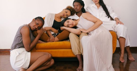 Diverse Expression. - Photo of Women Sitting on Orange Sofa