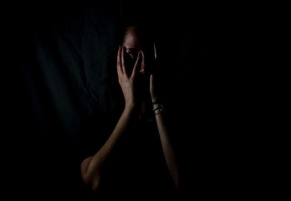Fear - woman holding her face in dark room