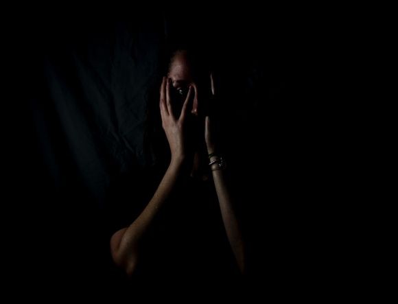 Fear - woman holding her face in dark room