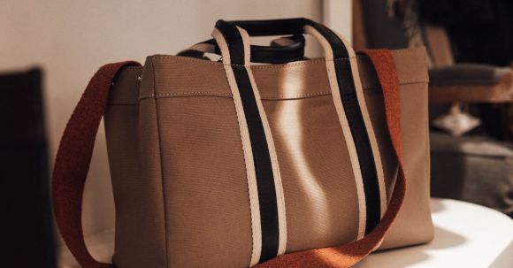 Choosing Handbag. - Stylish beige shopper bag with long strap placed on shelf in modern fashion boutique