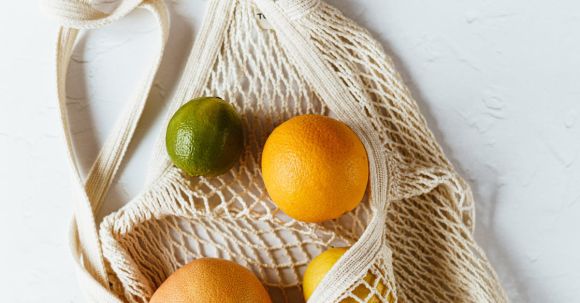 Reduce Waste, Combat Hunger - Assorted citrus fruits in cotton sack on white surface