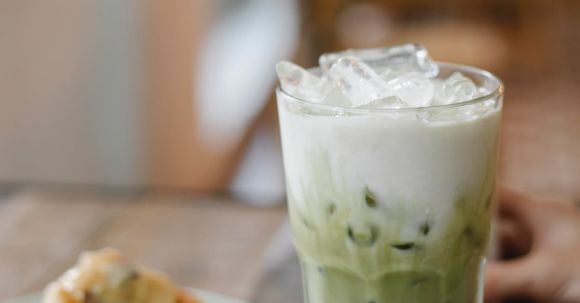 Decadent Dessert Recipes - Glass of tasty refreshing matcha latte served on table with yummy pie slice in cafe