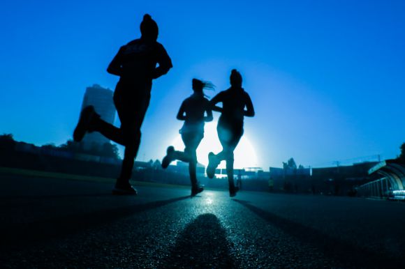 Running - silhouette of three women running on grey concrete road