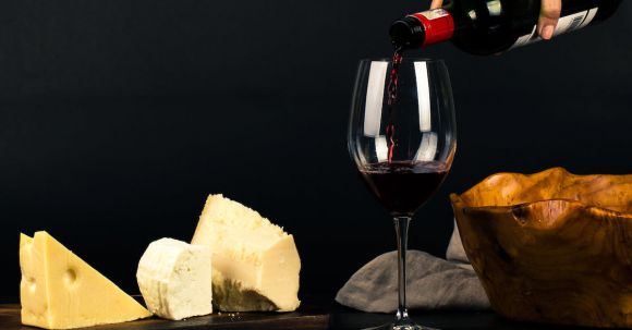 Cheese Pairings - Photo of Person Pouring Wine into Glass besides Some Cheese Pairings