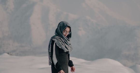 Wildlife Preservation, Responsible Tourism - Full body of female traveler in headscarf standing with acoustic guitar on snow against blurred highland