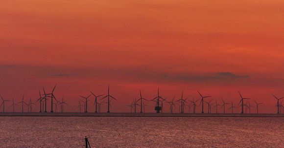 Renewable Wonders - Sailboat on calm lake with modern windmills on shore at sundown