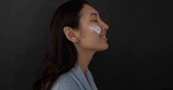 Mindful Nourishment - Smiling Asian woman with nourishing cream on cheek