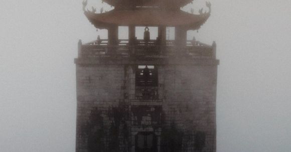 Ancient Mysteries - Tall Buddhist pagoda in dense fog