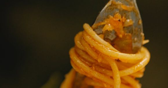 Authentic Pasta - Closeup of fork with appetizing Italian spaghetti Bolognese pasta with tomato sauce and green herbs