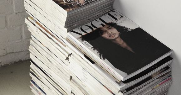 Everlasting Trend. - High angle many fashion magazines stacked on floor against white brick wall in studio